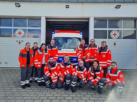 Die Teilnehmenden der Fachdienstausbildung Sanitätsdienst stehen als in Einsatzkleidung vor einem Einsatzfahrzeug