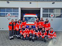 Die Teilnehmenden der Fachdienstausbildung Sanitätsdienst stehen als in Einsatzkleidung vor einem Einsatzfahrzeug