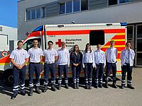 Die neuen Auszubildenden im Rettungsdienst stehen vor einem Rettungswagen