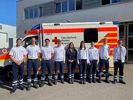 Die neuen Auszubildenden im Rettungsdienst stehen vor einem Rettungswagen