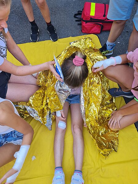Eine Gruppe Juniorhelferinnen hilft einem verletzten Mädchen