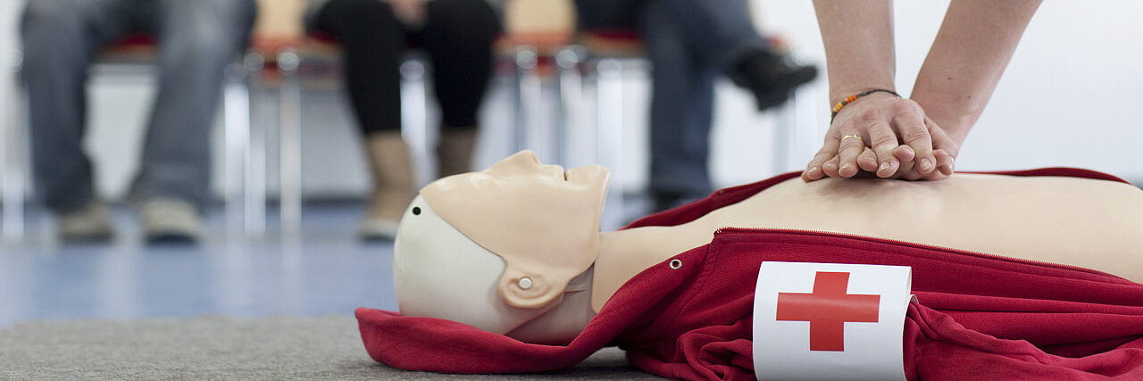 Mensch übt in einem Erste-Hilfe-Kurs an einer Puppe die Wiederbelebung
