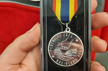 Eine Hand hält die Medaille in die Kamera