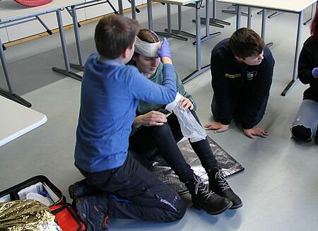 Kinder legen einem verletzten Kind ein Verband an