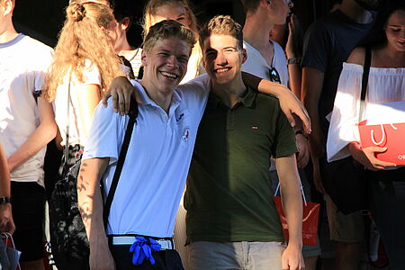 Zwei Freiwillige blicken bei ihrem Abschiedsfest lächelnd in die Kamera