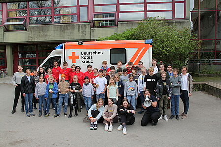 Kinder und Jugendliche stehen als Gruppe vor einem Rettungswagen