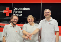 Die neue Leiterin und ihre Stellvertreter des Kreisauskunftsbüros stehen vor einem Einsatzfahrzeug.