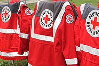 Rotkreuz-Einsatzjacken hängen über Stühlen.