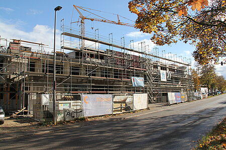 Der Rohbau des Neubaus ist von der Straße aus zu sehen mit Gerüsten und Kränen