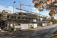 Der Rohbau des Neubaus ist von der Straße aus zu sehen mit Gerüsten und Kränen