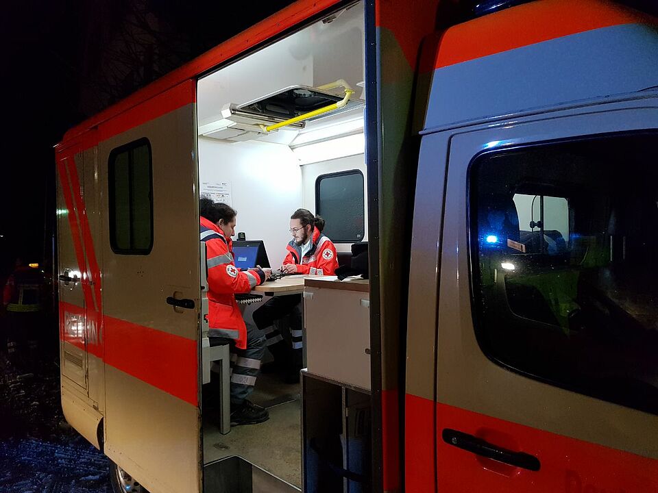 Einsatzkräfte der Personenauskunftsstelle sitzen in ihrem Einsatzfahrzeug.