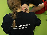 Eine Jugendrotkreuzlerin schminkt bei einer Übung eine Verletzung an einen Oberschenkel.