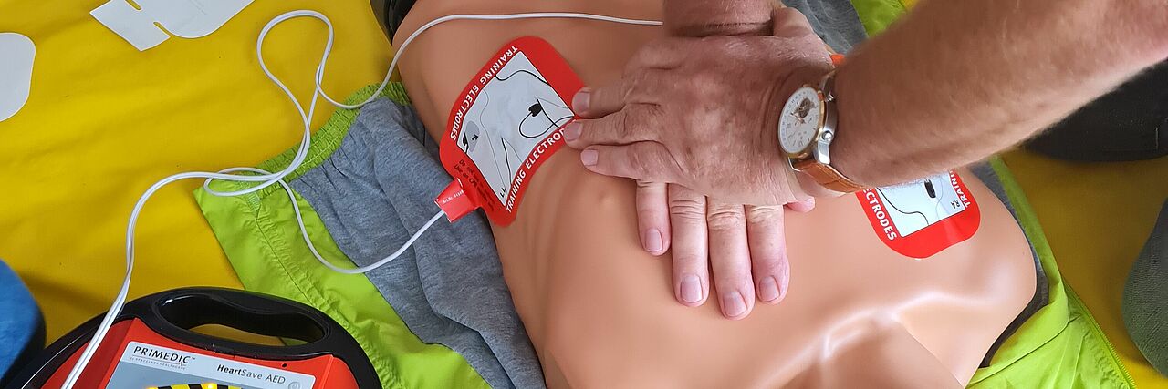 Wiederbelebung Ein Mann übt die Wiederbelebung an einer Puppe und benutzt einen AED